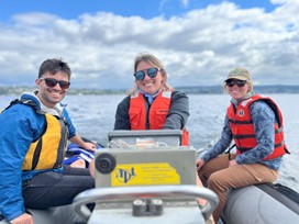 Three UW researchers in a boat wearing life jackets Three UW researchers in a boat wearing life jackets